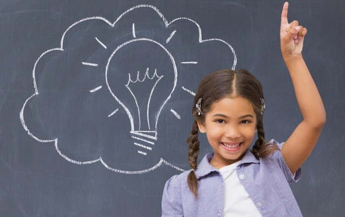 Schoolgirl raising her hand in front of a blackboard