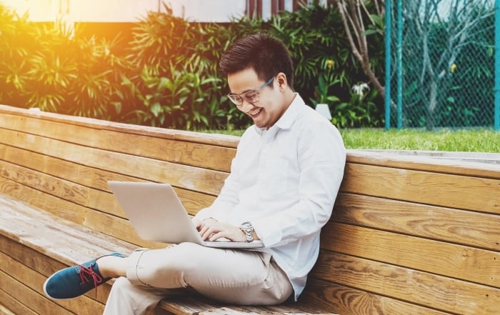 Young happy businessman working on laptop at garden